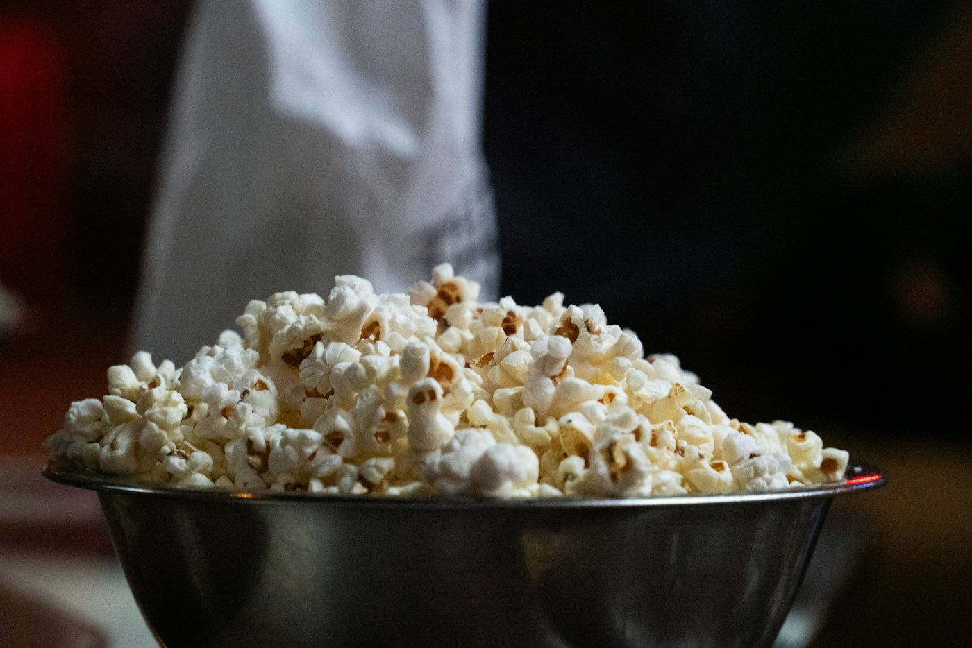 Metal bowl overflowing with freshly popped popcorn, a common late-night snack