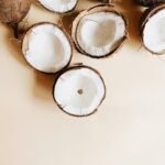 Halved and whole coconuts on a white surface