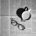 Cup of coffee and a pair of glasses resting on a newspaper