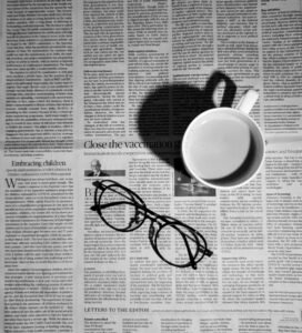 Cup of coffee and a pair of glasses resting on a newspaper