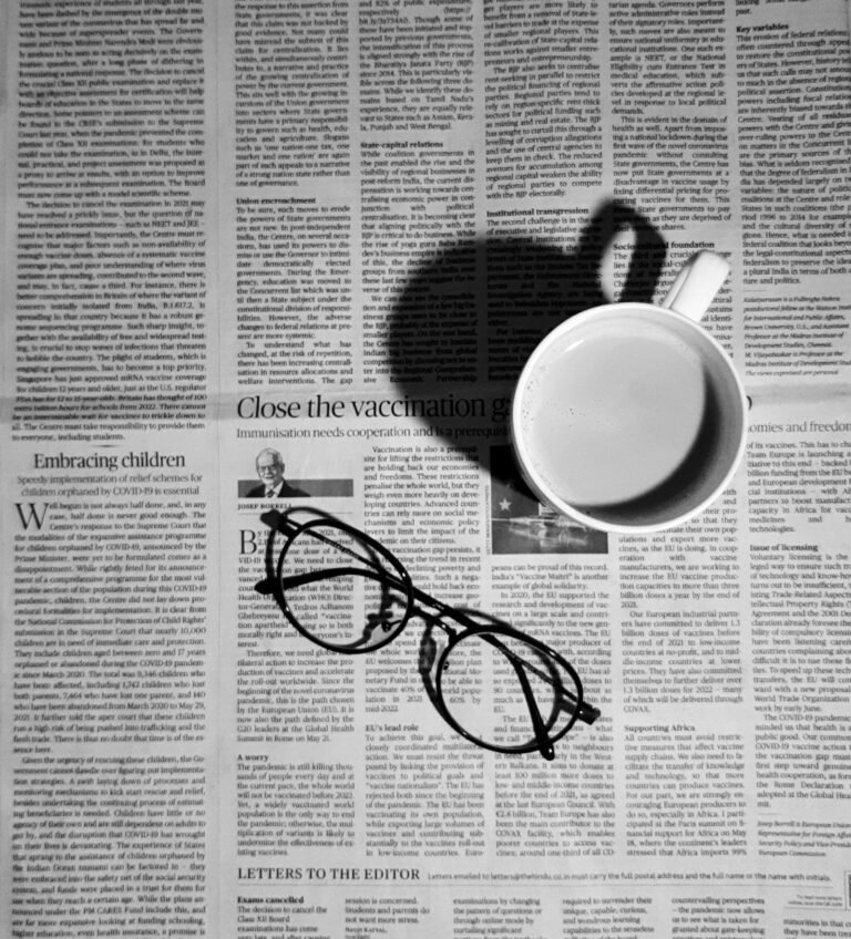 Cup of coffee and a pair of glasses resting on a newspaper
