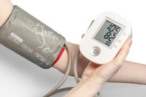 Person measuring blood pressure with a digital monitor and grey arm cuff