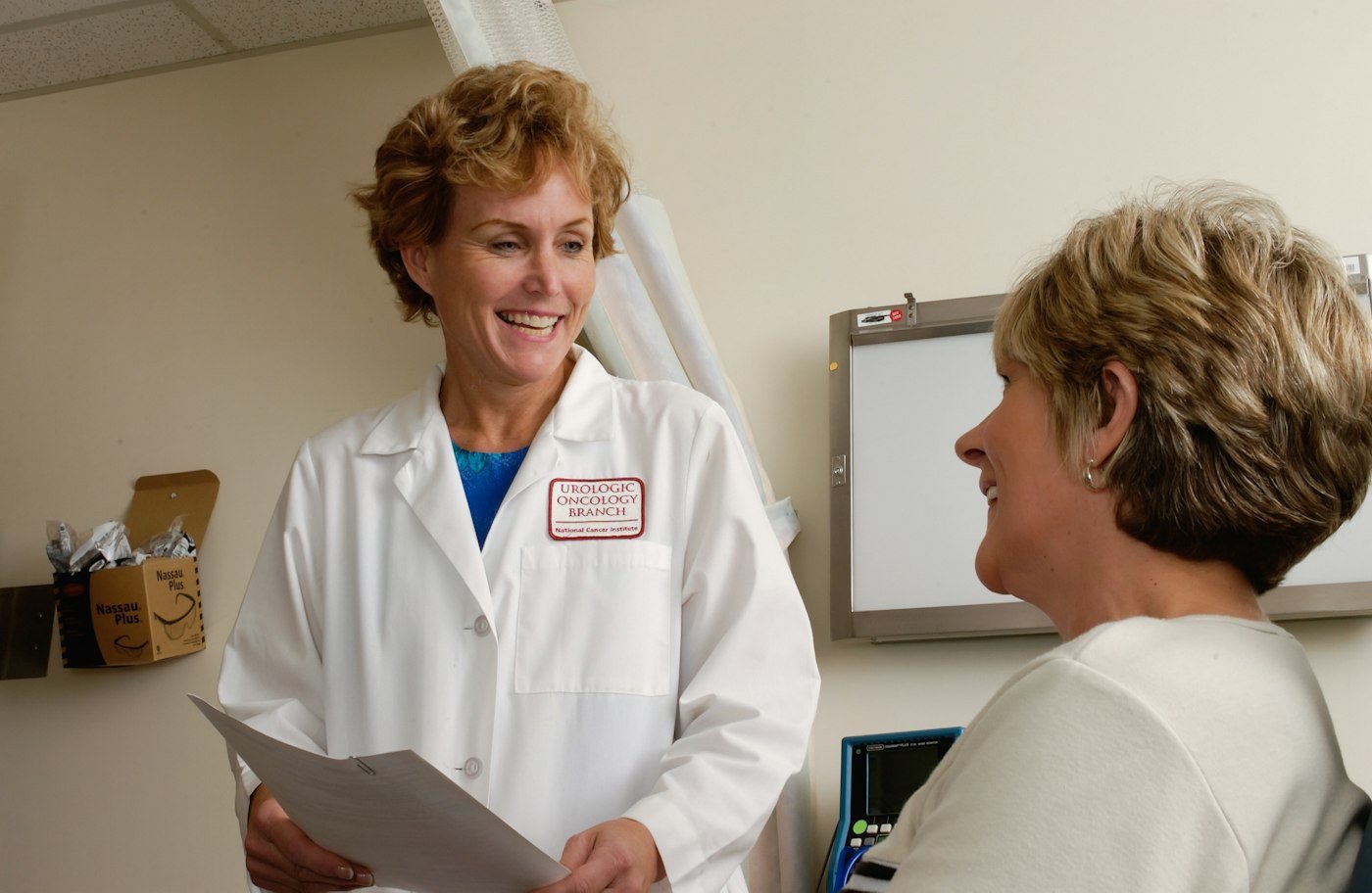 Smiling doctor in a white coat talking with a patient in a clinic