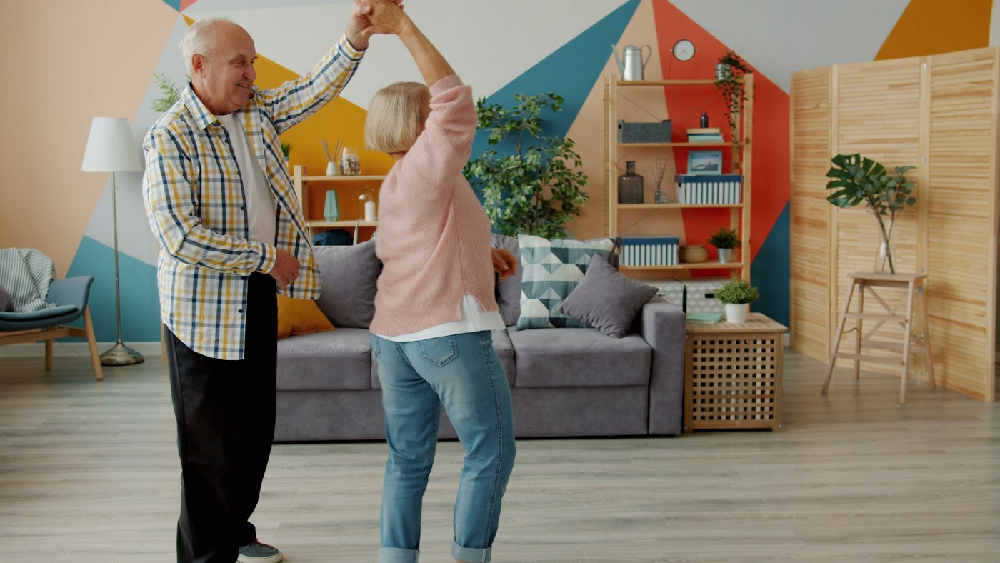 Elderly couple dancing joyfully in their living room