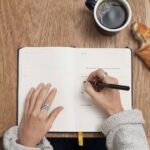 Person writing in a notebook, keeping a food journal for weight loss