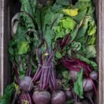 Fresh beets with green leaves in a wooden crate