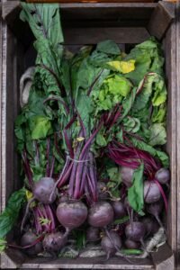 Fresh beets with green leaves in a wooden crate