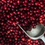 A scoop of fresh red cranberries on a table