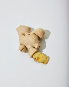Fresh ginger root and a cut piece of ginger on a white surface