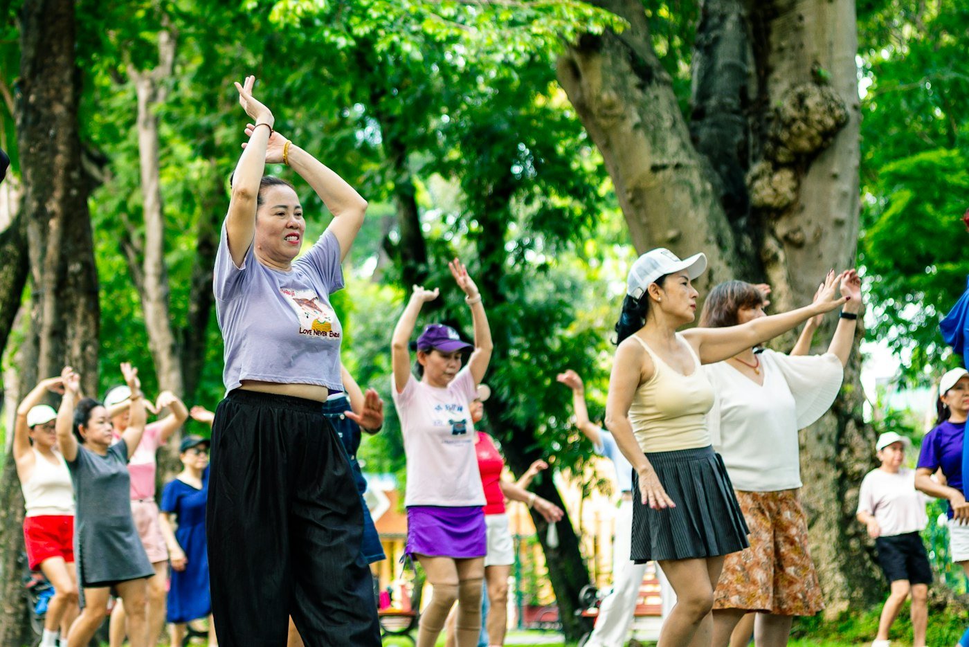 Group of people doing slow, flowing exercise outdoors in a park
