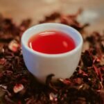 White ceramic cup filled with deep red hibiscus tea