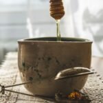 Golden honey pouring from a spoon into a bowl