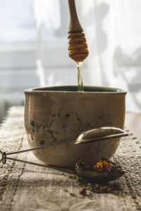 Golden honey pouring from a spoon into a bowl