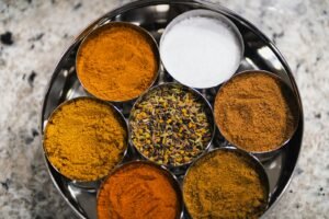 Various colorful kitchen spices arranged in metal bowls on a tray