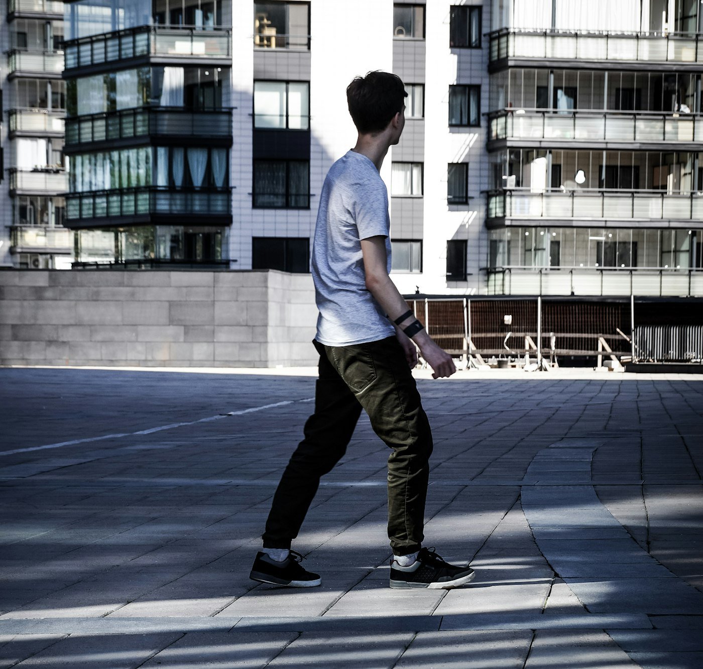 Man walking at a fast pace on a brick pavement near a white building