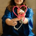 Woman in scrubs holding a heart-shaped stethoscope