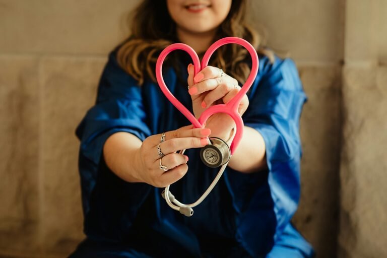 Woman in scrubs holding a heart-shaped stethoscope