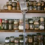 Assorted glass jars of grains, beans, and seeds on a white wooden shelf