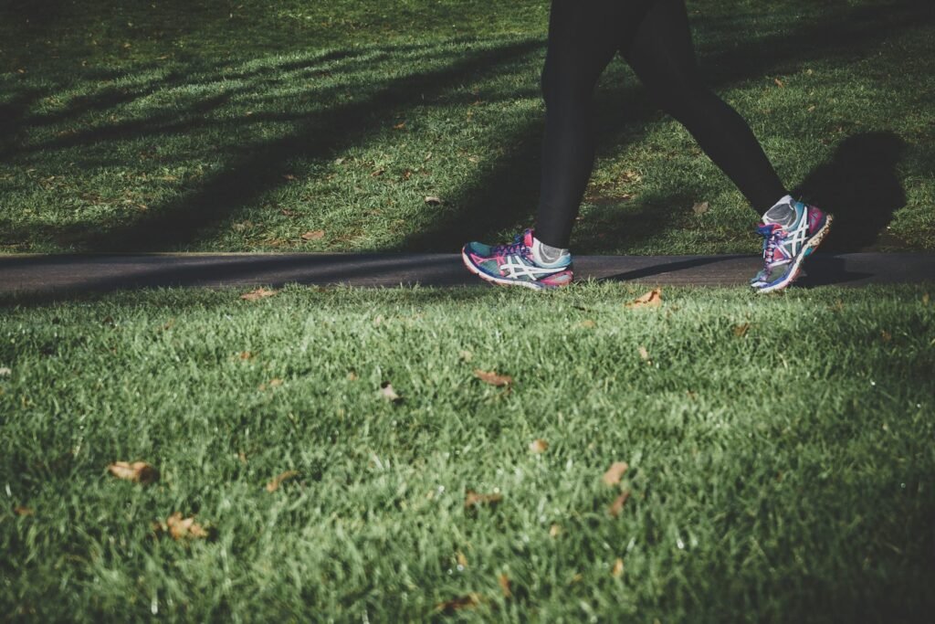 Person walking briskly on a road between grassy fields