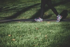Person walking briskly on a road between grassy fields