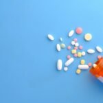 Colorful pills spilling out of an orange prescription bottle