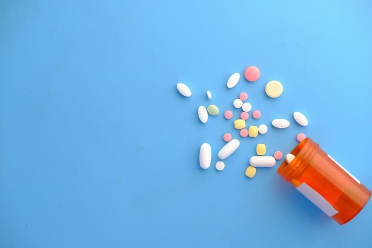 Colorful pills spilling out of an orange prescription bottle