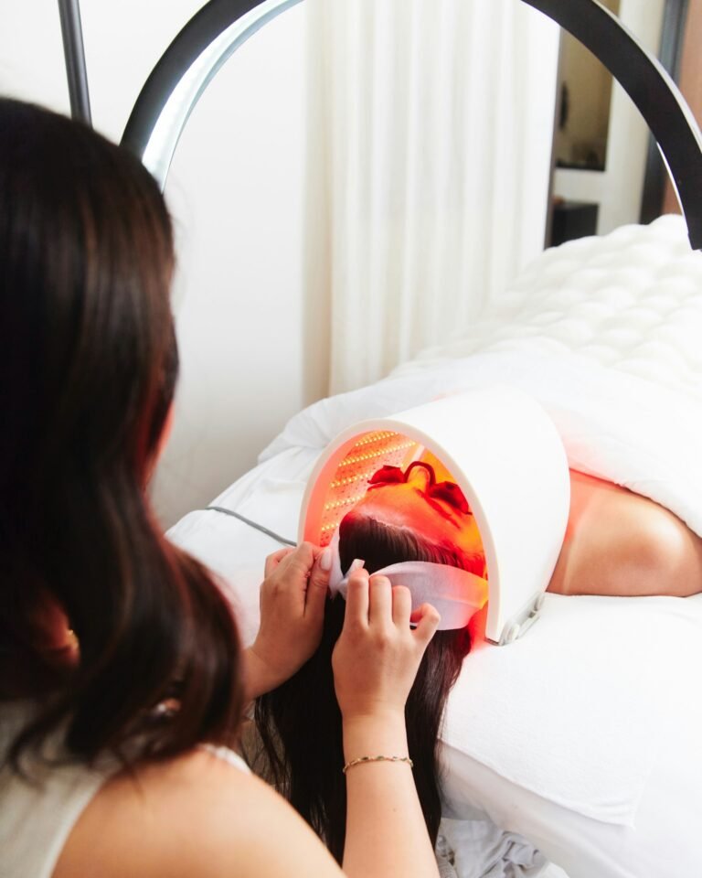 Woman relaxing under a red light therapy device during a spa treatment