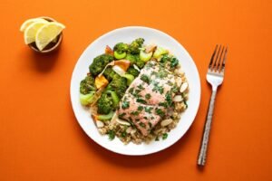 Salmon fillet with herbs on quinoa beside roasted broccoli on a plate