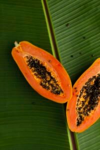 Sliced ripe papaya with its black seeds on a green banana leaf