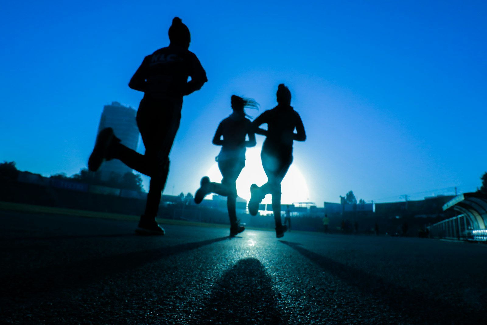 Silhouette of three women running together on a road