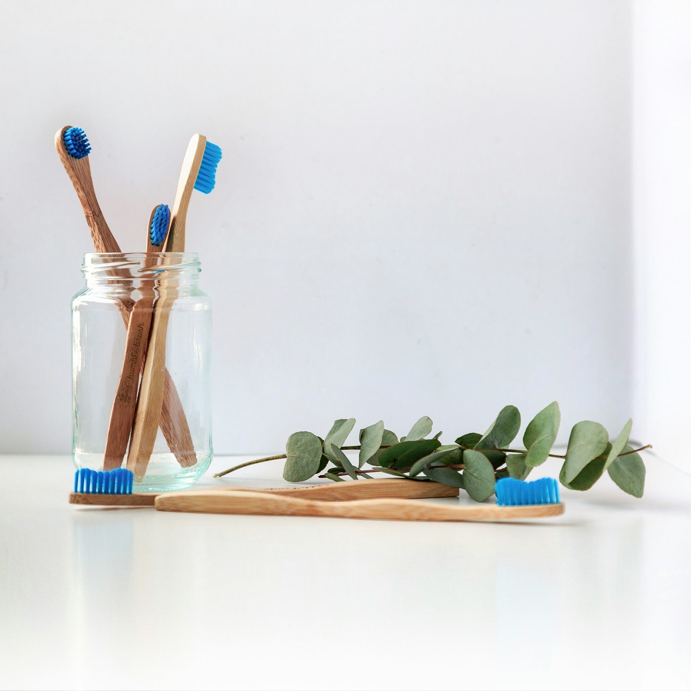 Blue and white toothbrush standing in a clear glass jar