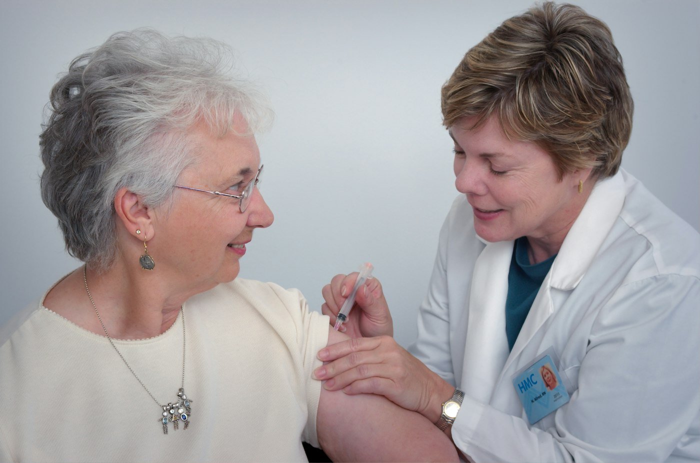 Health worker giving a woman a vaccine in the upper arm