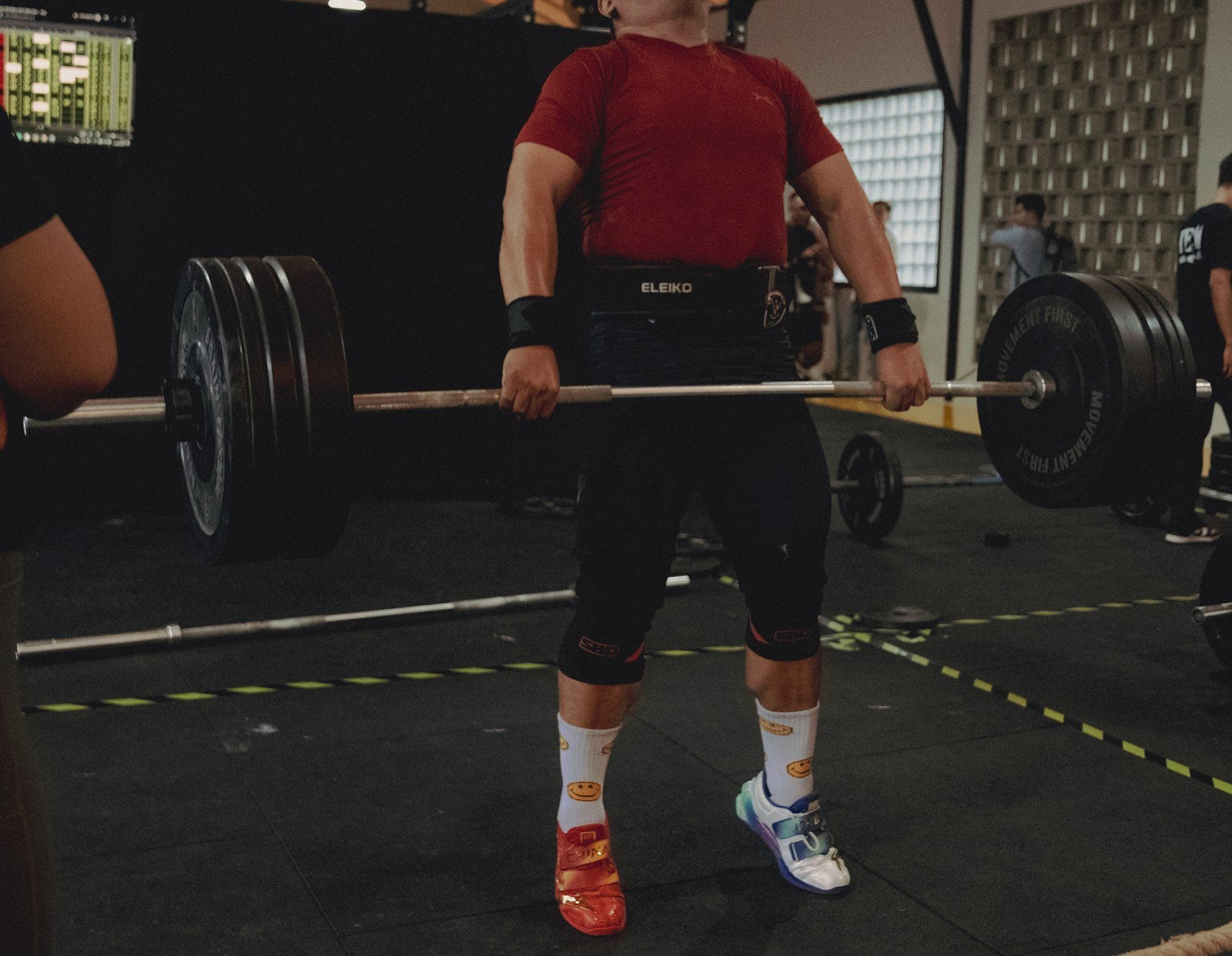 Weightlifter performing a deadlift with a heavy barbell in a gym