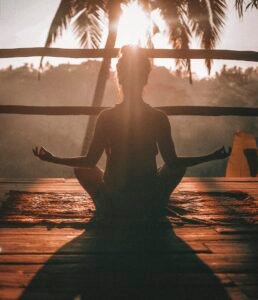 Woman sitting in a calm yoga meditation pose on a wooden floor