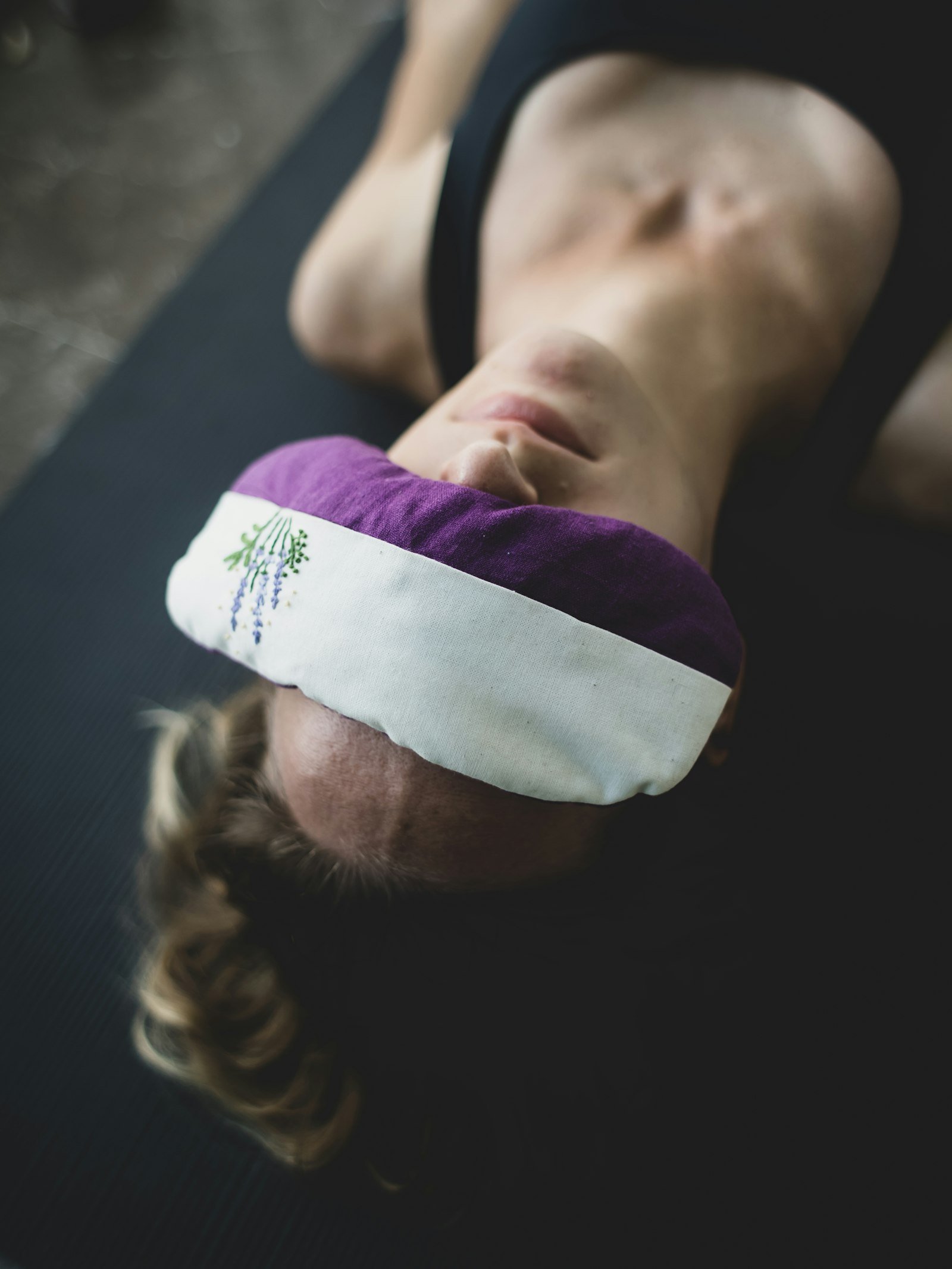 A woman resting with an eye pillow on her forehead during deep relaxation